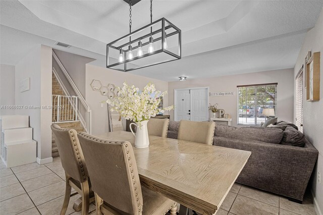 dining space featuring an inviting chandelier, a textured ceiling, and light tile patterned flooring