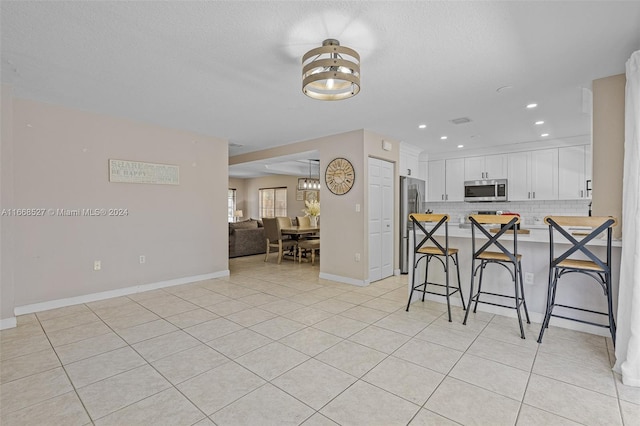 kitchen with stainless steel appliances, a breakfast bar, a chandelier, and white cabinetry