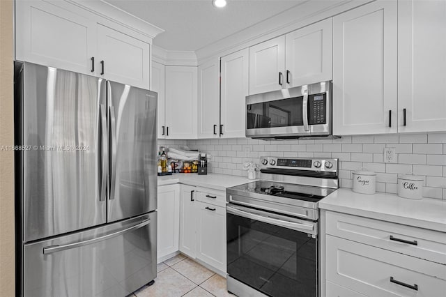 kitchen featuring appliances with stainless steel finishes, decorative backsplash, light tile patterned flooring, white cabinetry, and a textured ceiling