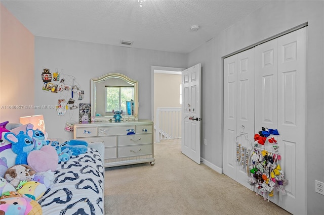 bedroom featuring light carpet, a closet, and a textured ceiling