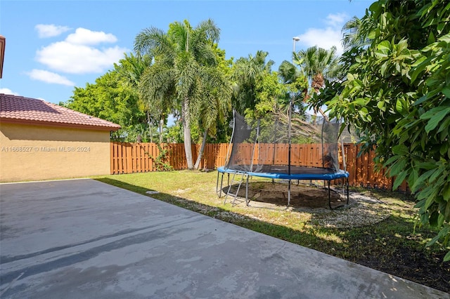 view of yard with a trampoline and a patio area