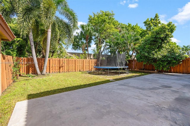 view of yard with a trampoline and a patio area