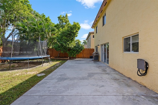 exterior space featuring a trampoline, a lawn, and a patio