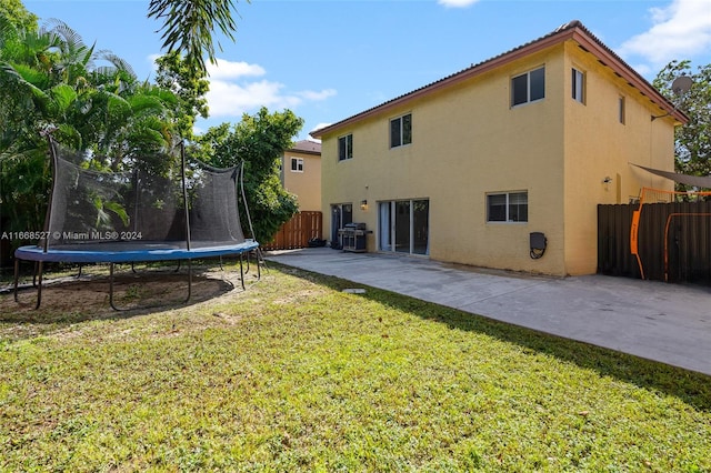 back of house featuring a trampoline, a yard, and a patio