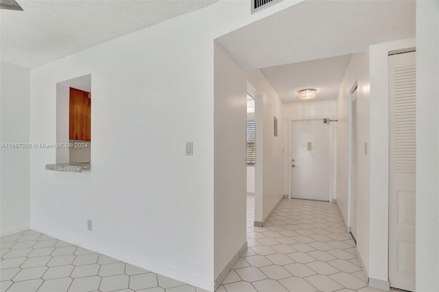 hallway with light tile patterned floors and a textured ceiling