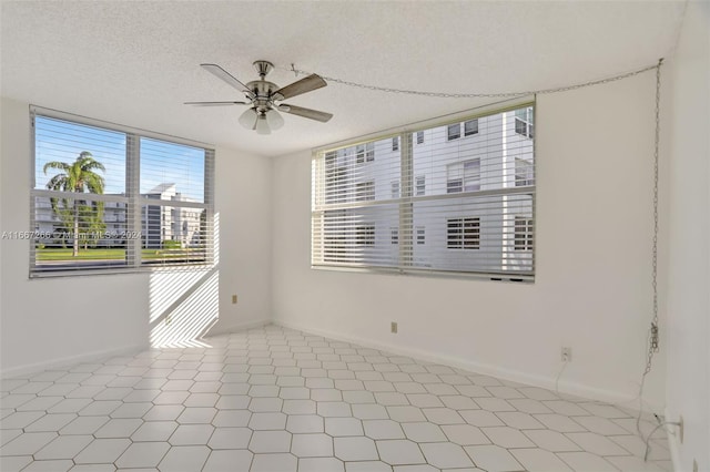 empty room featuring a textured ceiling, ceiling fan, and light tile patterned flooring