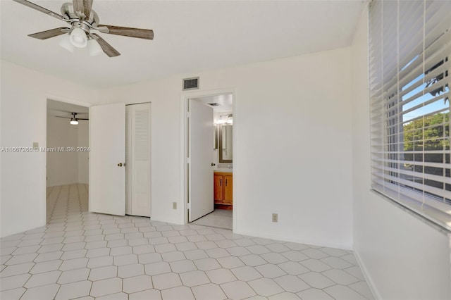 unfurnished bedroom with light tile patterned flooring, connected bathroom, a closet, and ceiling fan