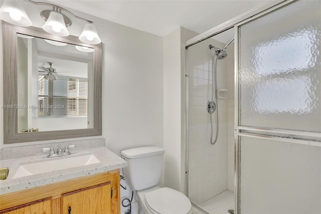 bathroom featuring vanity, toilet, an enclosed shower, and ceiling fan