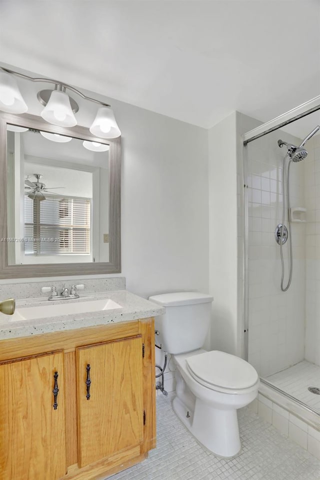 bathroom featuring ceiling fan, tile patterned flooring, toilet, a shower with door, and vanity