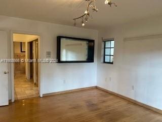 empty room with an inviting chandelier and hardwood / wood-style flooring