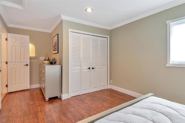 bedroom with a closet, crown molding, and dark hardwood / wood-style flooring