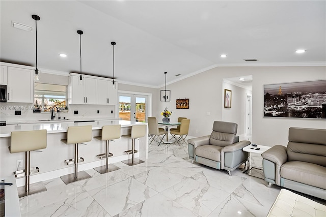 interior space with a breakfast bar, pendant lighting, white cabinets, and lofted ceiling