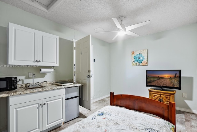 bedroom featuring ceiling fan, light hardwood / wood-style floors, sink, and a textured ceiling