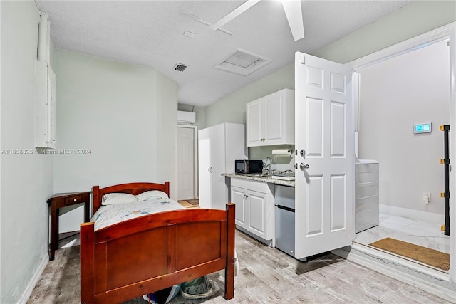 kitchen featuring white cabinets, a textured ceiling, a wall mounted AC, and light hardwood / wood-style flooring