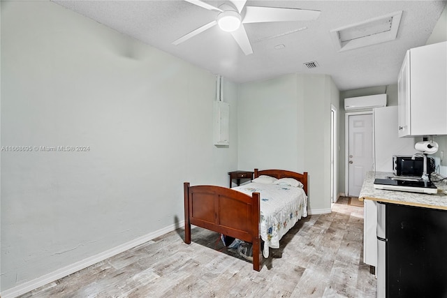 bedroom with a wall mounted AC, a textured ceiling, light hardwood / wood-style flooring, and ceiling fan