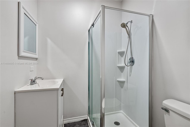 bathroom featuring vanity, a shower with shower door, and toilet