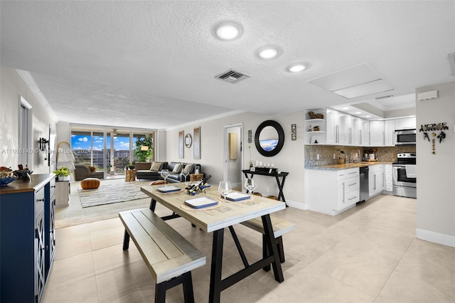 dining area featuring ornamental molding, a textured ceiling, light tile patterned floors, and sink