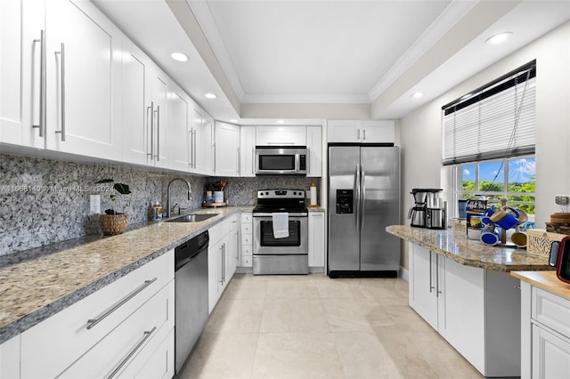 kitchen featuring white cabinetry, light stone counters, stainless steel appliances, ornamental molding, and sink