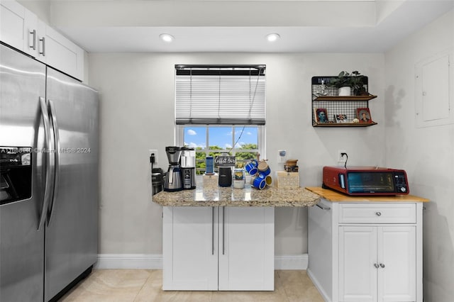 kitchen with light stone counters, white cabinets, light tile patterned flooring, and stainless steel fridge with ice dispenser