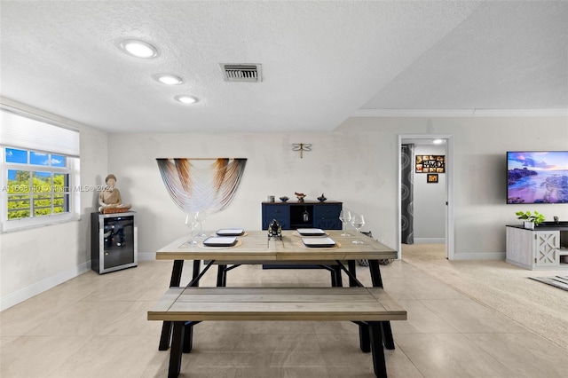 dining space with beverage cooler, a textured ceiling, light tile patterned floors, and crown molding