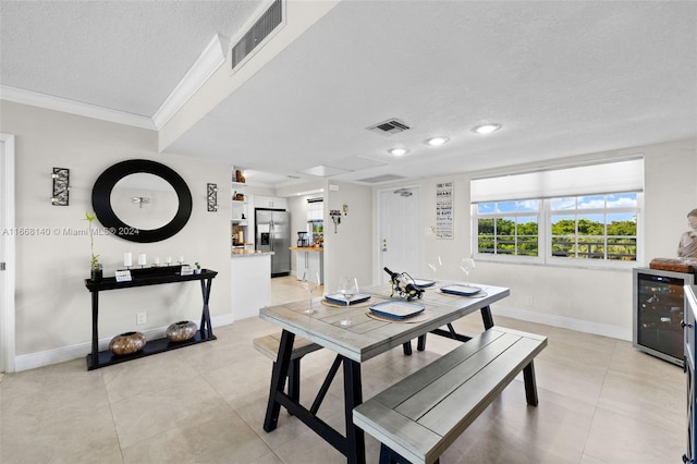 dining space with beverage cooler, a textured ceiling, light tile patterned floors, and crown molding