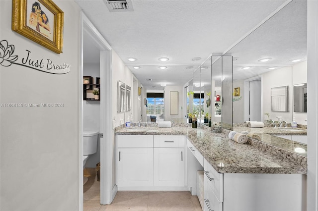 bathroom featuring tile patterned floors, a textured ceiling, vanity, and toilet