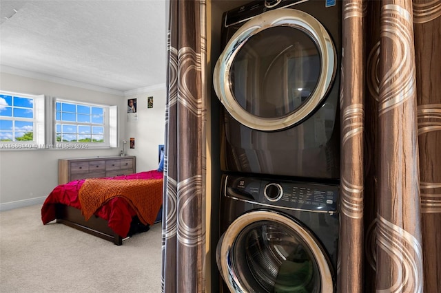 clothes washing area with light carpet, a textured ceiling, crown molding, and stacked washing maching and dryer