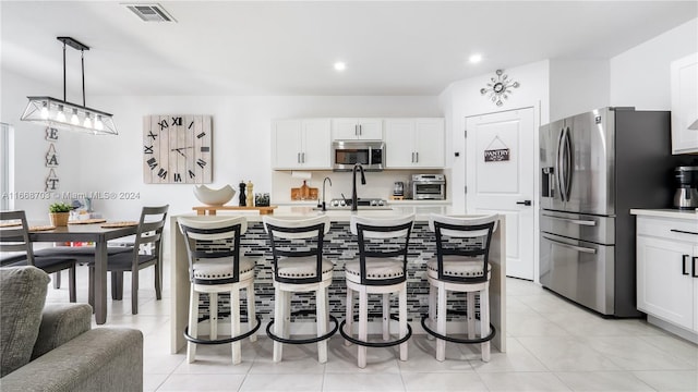 kitchen featuring an island with sink, stainless steel appliances, white cabinetry, and sink