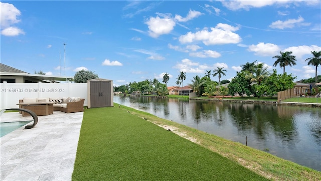 view of swimming pool with a patio, a storage unit, a water view, and pool water feature