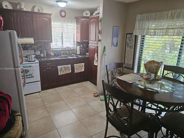 kitchen featuring backsplash, white appliances, light tile patterned floors, a textured ceiling, and sink