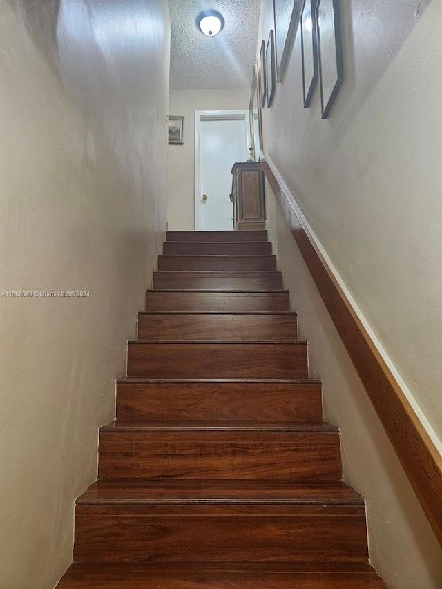 stairs featuring a textured ceiling