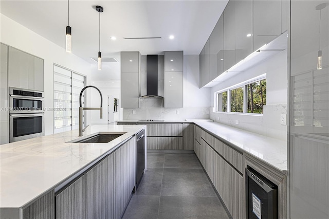 kitchen with gray cabinetry, wall chimney range hood, and sink