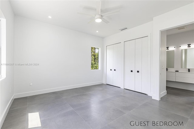 unfurnished bedroom featuring multiple closets, concrete flooring, and ceiling fan