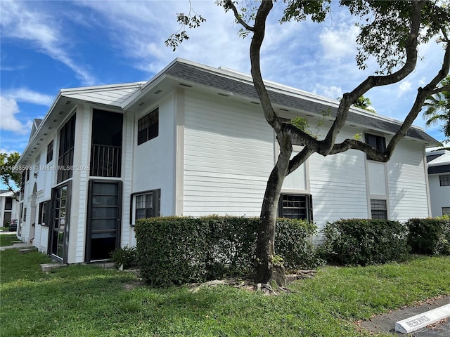 view of property exterior with roof with shingles and a lawn