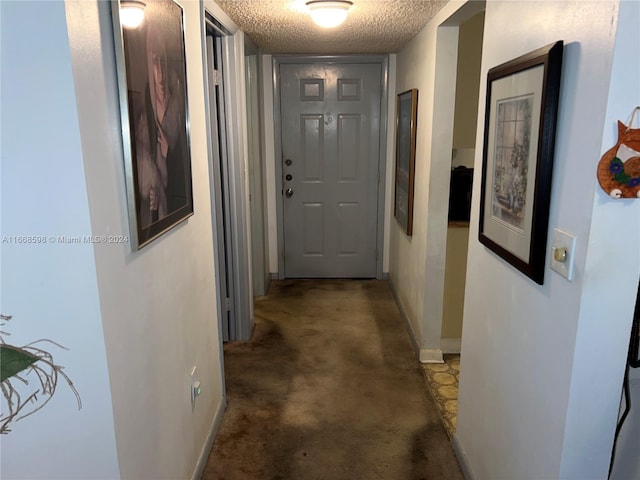 corridor with a textured ceiling and dark colored carpet