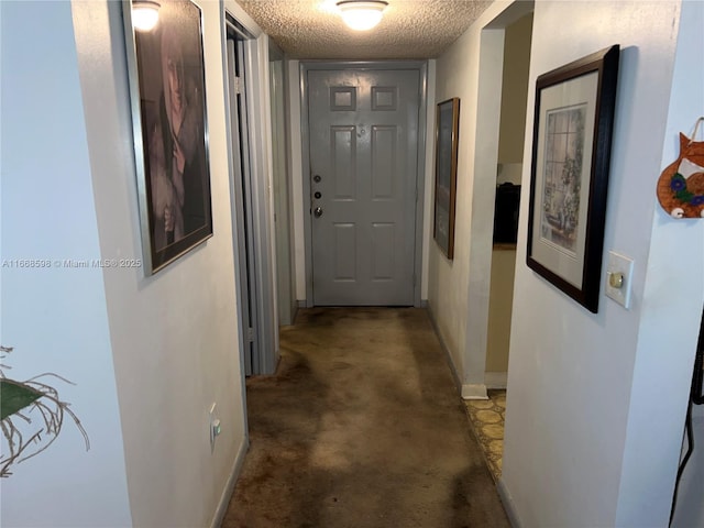 hall featuring a textured ceiling and baseboards