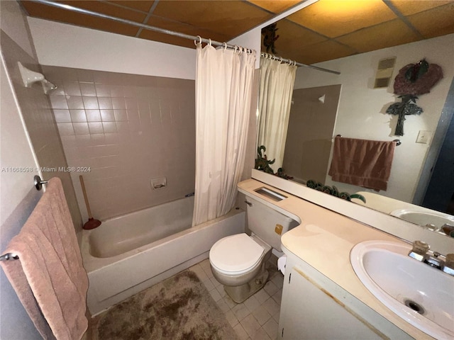 full bathroom featuring vanity, a paneled ceiling, shower / bath combo with shower curtain, tile patterned floors, and toilet