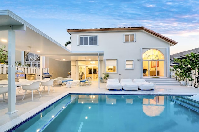 back of property with an outdoor pool, a patio, and stucco siding