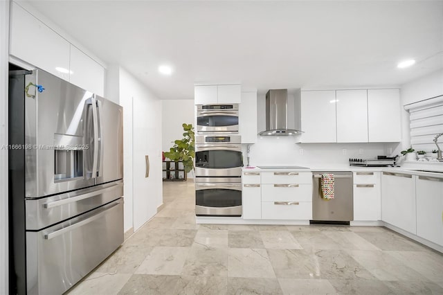 kitchen featuring modern cabinets, appliances with stainless steel finishes, light countertops, wall chimney range hood, and white cabinetry