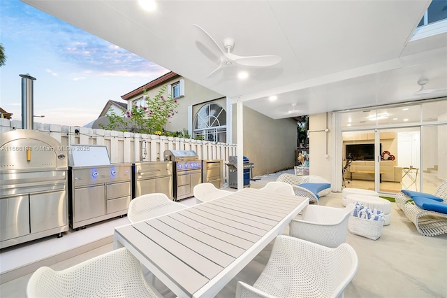 view of patio / terrace with grilling area, a ceiling fan, outdoor dining area, and exterior kitchen