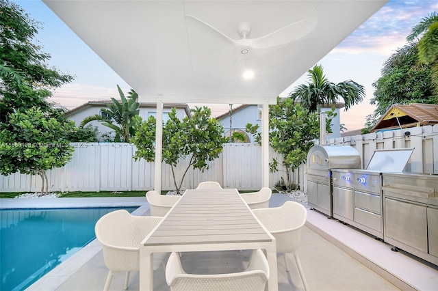 view of swimming pool with an outdoor kitchen, a fenced backyard, area for grilling, a ceiling fan, and a fenced in pool