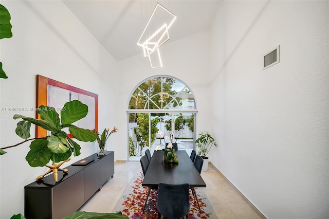 dining space with visible vents, a notable chandelier, and a towering ceiling