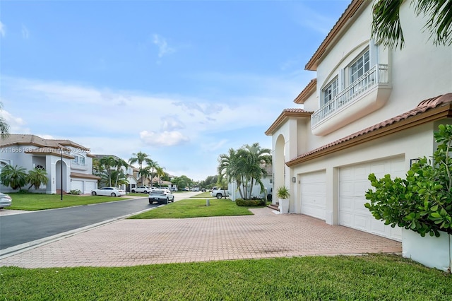 exterior space featuring a garage, a residential view, and decorative driveway