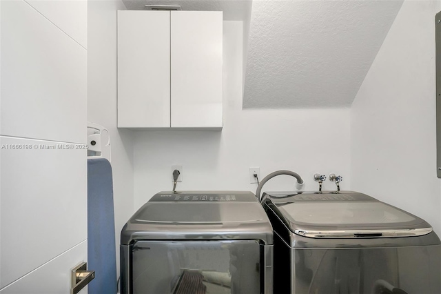 laundry area featuring washing machine and dryer, cabinet space, and a textured ceiling