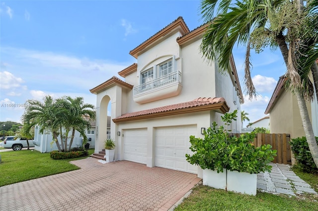 mediterranean / spanish home featuring a balcony, a garage, decorative driveway, and stucco siding