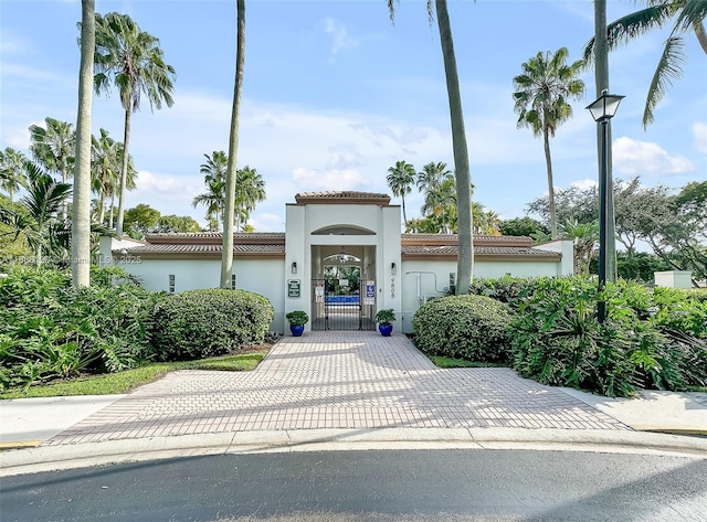 view of front of house with driveway, a garage, a tiled roof, a gate, and stucco siding