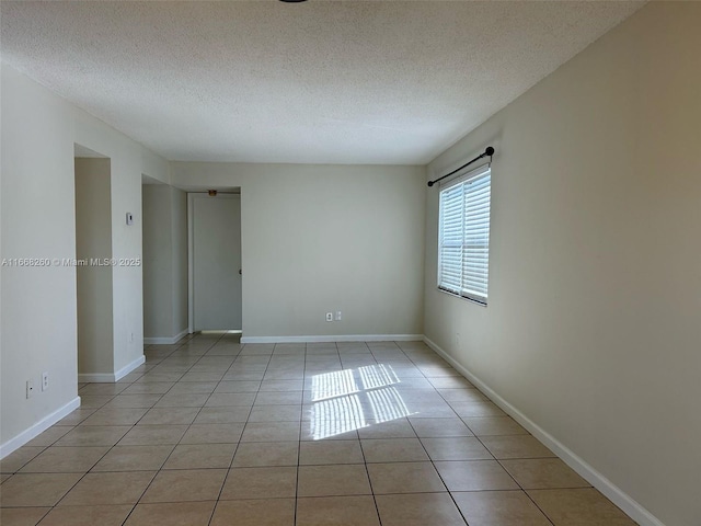 unfurnished room featuring light tile patterned flooring, baseboards, and a textured ceiling