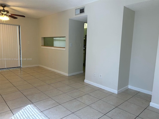 empty room with visible vents, baseboards, light tile patterned floors, a textured ceiling, and a ceiling fan