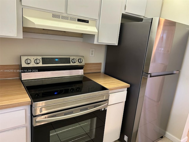 kitchen with under cabinet range hood, appliances with stainless steel finishes, white cabinets, and butcher block counters