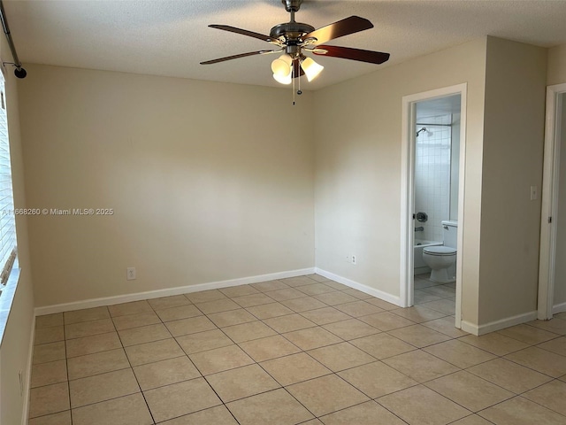 empty room featuring light tile patterned floors, a ceiling fan, baseboards, and a textured ceiling